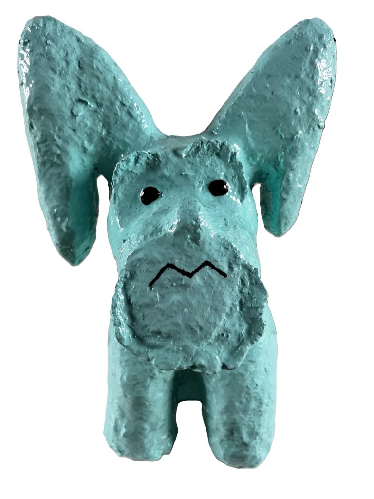 Turquoise dog sculpture with sad expression.