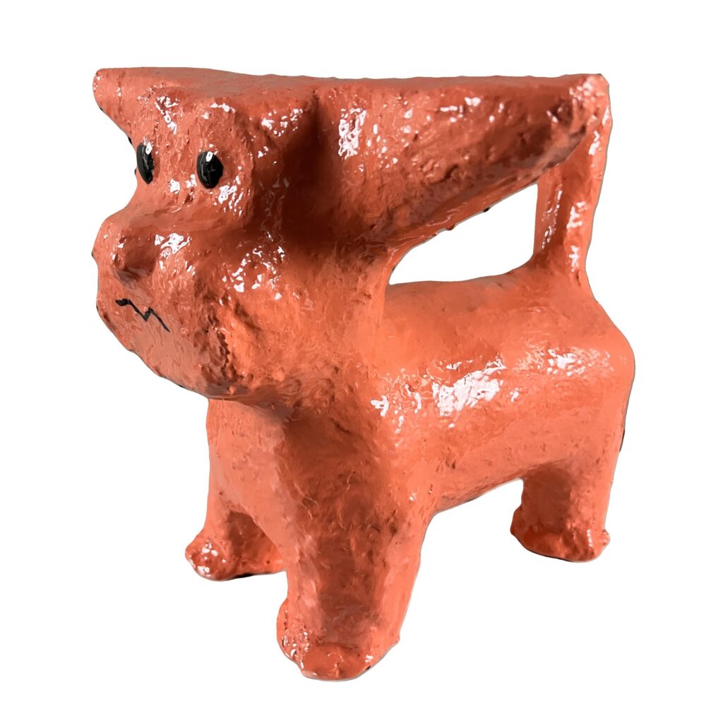 Orange dog sculpture with expressive face.